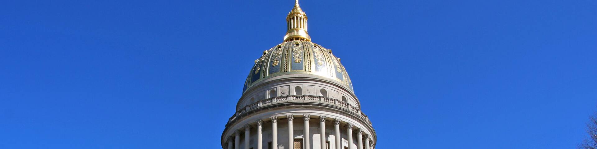 The West Virginia Capitol glows in the sun with the Abraham Lincoln statue in the foreground.