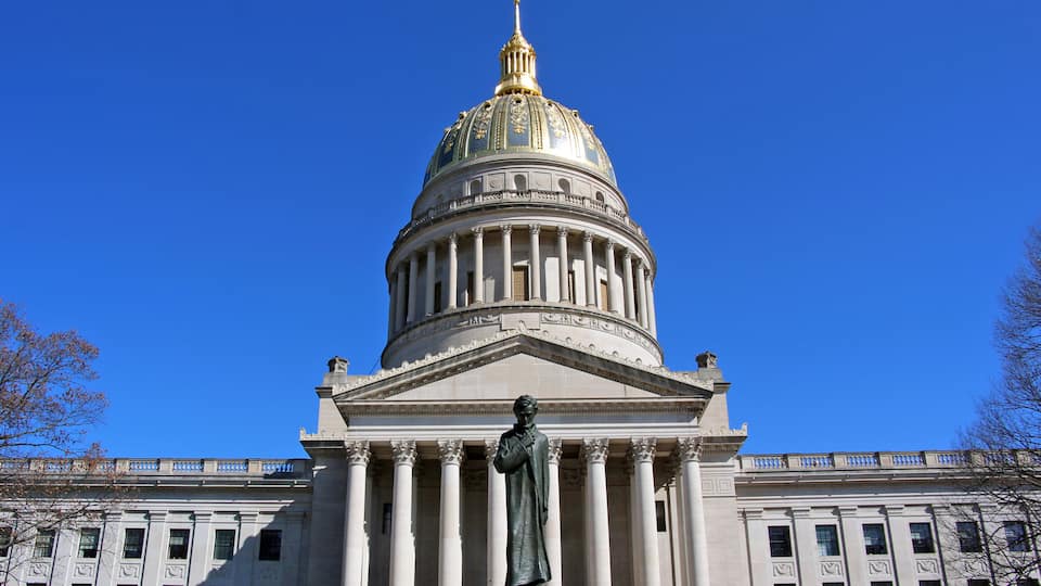 The West Virginia Capitol glows in the sun with the Abraham Lincoln statue in the foreground.