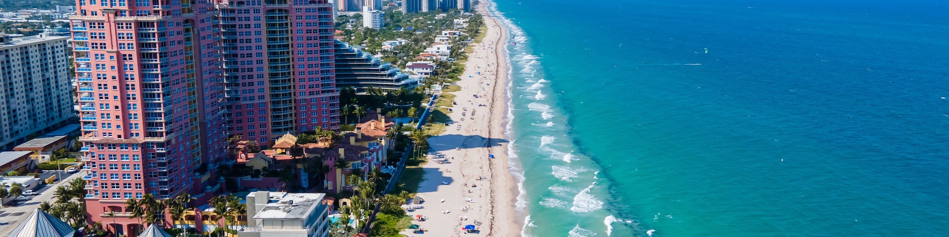 Un paisaje urbano costero con hoteles de gran altura, una playa arenosa y un océano azul y despejado.