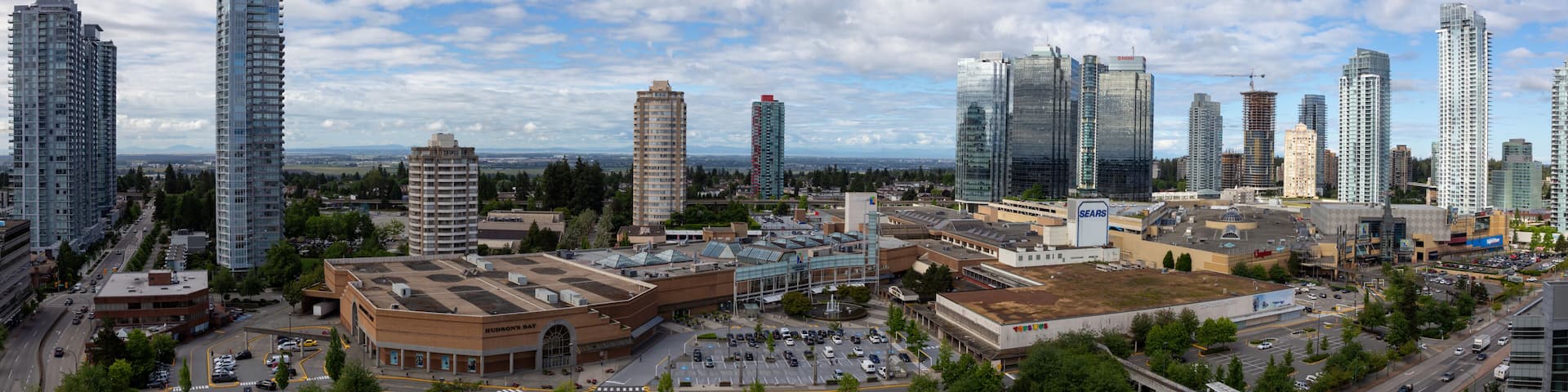A cityscape with high-rise buildings, a large parking lot, and a prominent Sears store.