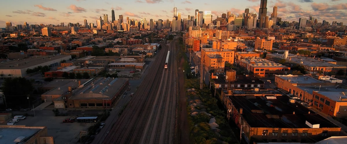 A cityscape with a prominent train track running through the center, surrounded by various buildings and skyscrapers.