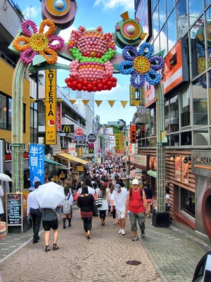 A busy street with colorful balloon decorations and various shops.