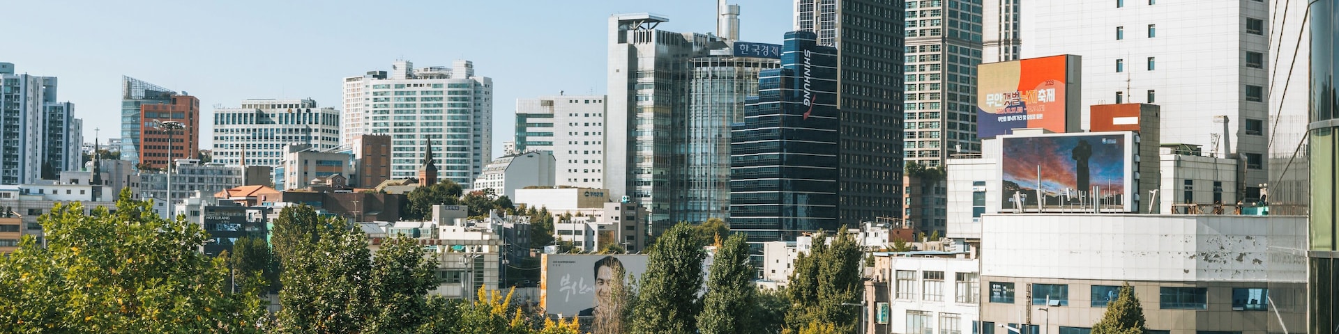 Paisagem urbana com edifícios modernos e arranha-céus, uma combinação de construções comerciais e residenciais, e céu claro.