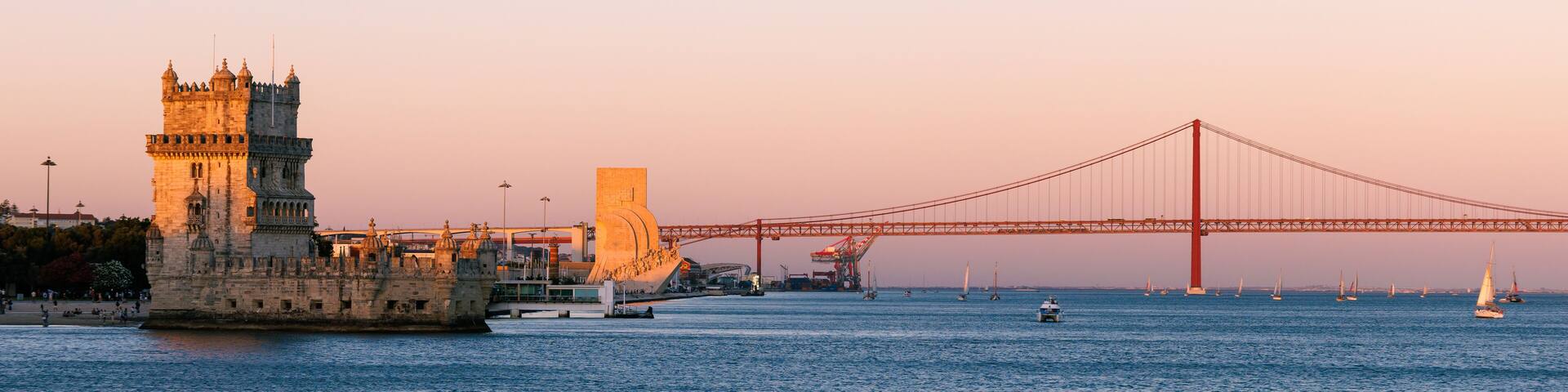 Panorama of Belém in Lisbon, the capital of Portugal. Sunset over Tagus river. Cityscape with Torre de Belém, Belém Tower and red iconic 25 de Abril Bridge, 25th of April Bridge.