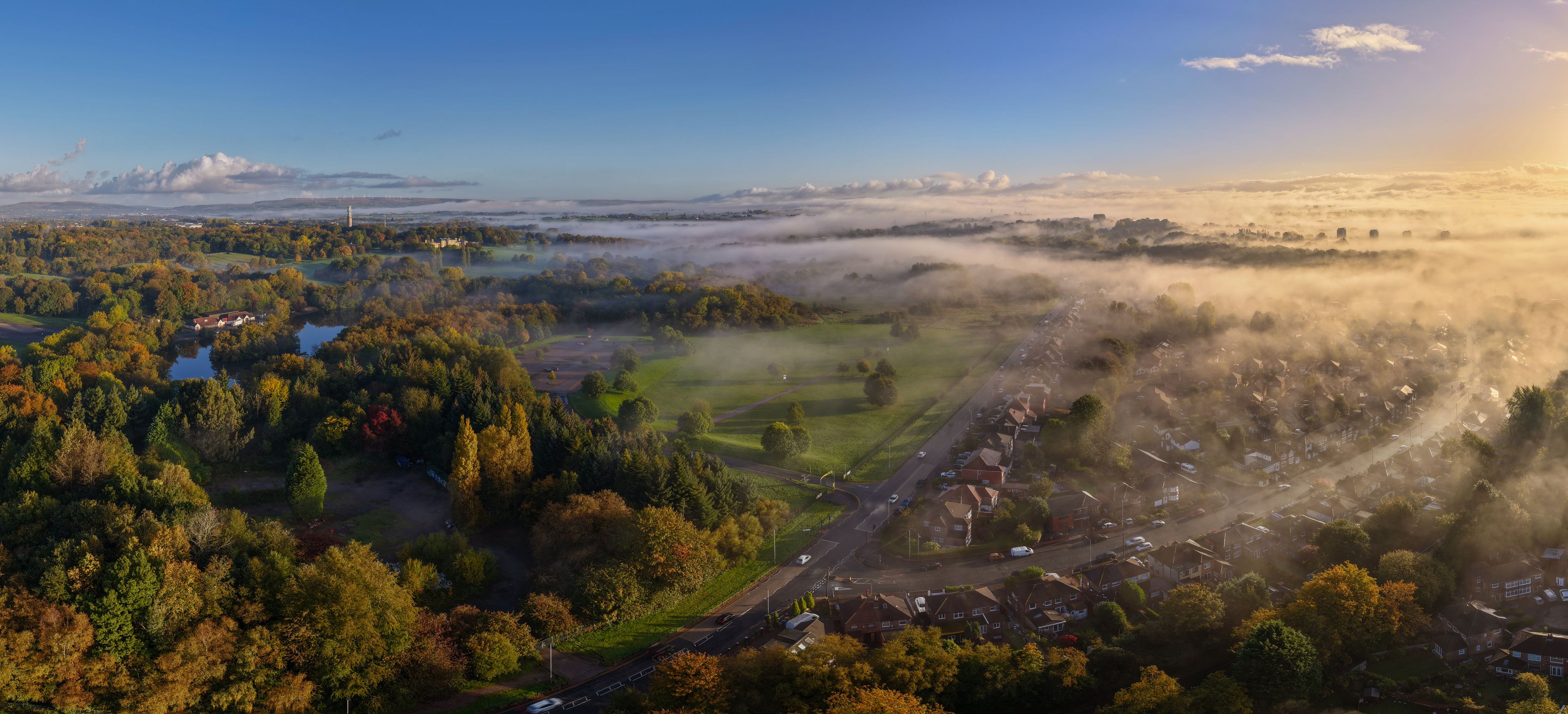 A misty landscape with a river, a road, and a residential area.