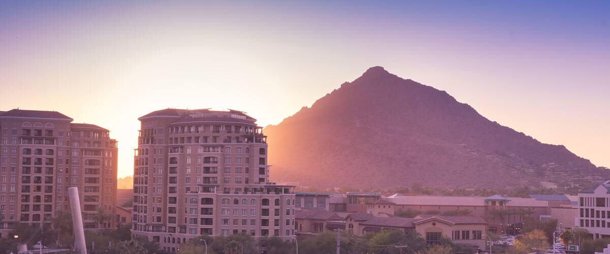 Sun setting over Scottsdale, Arizona waterfront area with Camelback Mountain glowing.