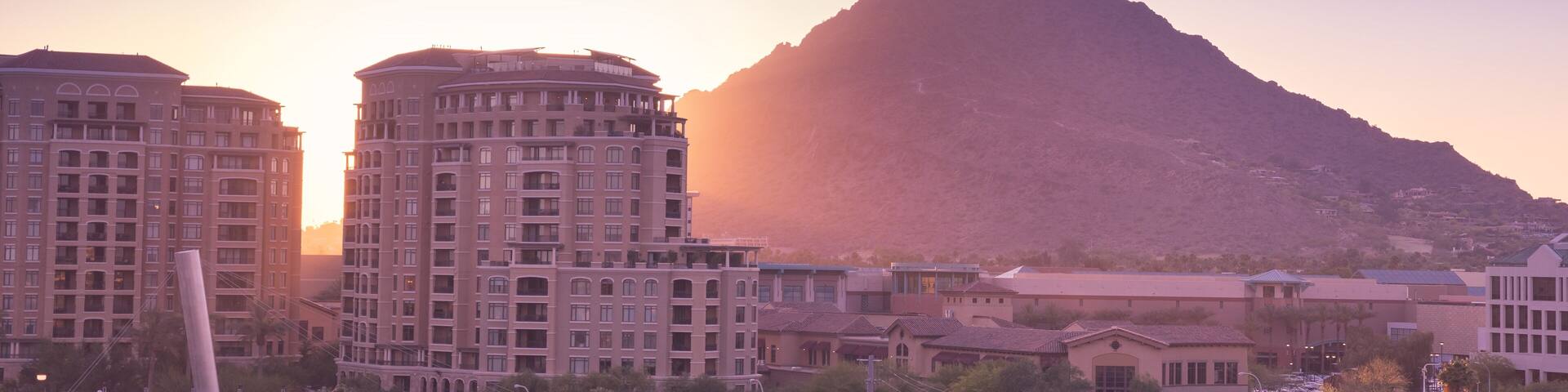 Sun setting over Scottsdale, Arizona waterfront area with Camelback Mountain glowing.