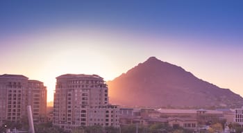 Sun setting over Scottsdale, Arizona waterfront area with Camelback Mountain glowing.