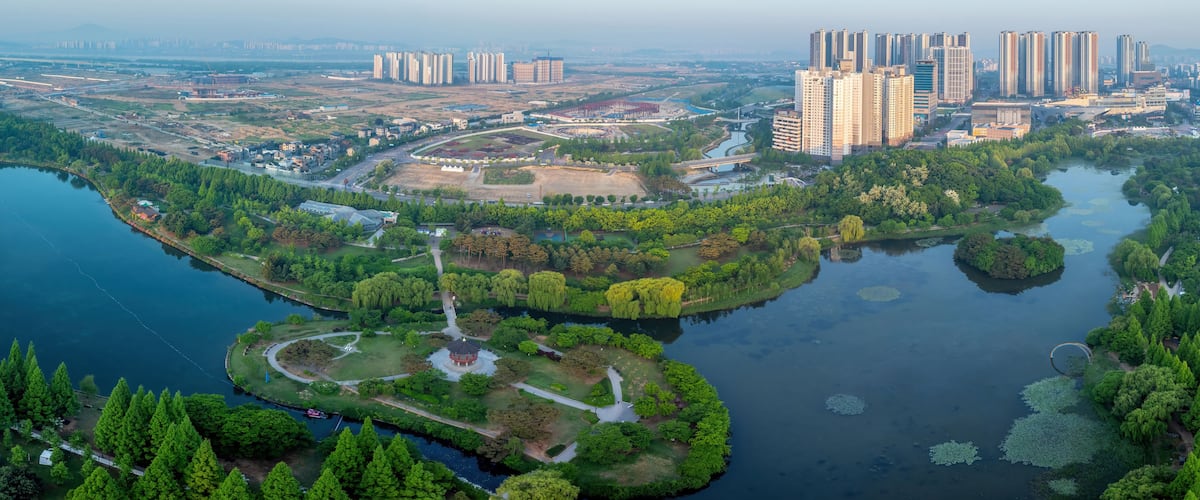 Un río serpentea por un parque con altos edificios al fondo.