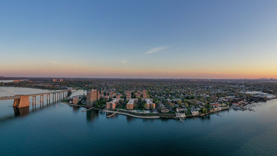 A bridge spanning a river, a cityscape with buildings, and a sunset.