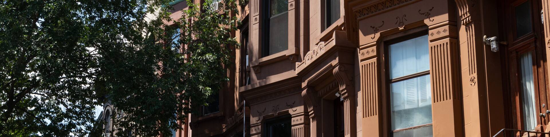 A row of brownstone buildings with ornate architectural details, including columns and decorative moldings.