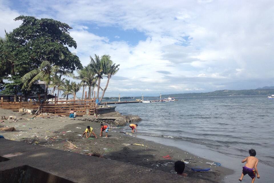 Una playa con palmeras, barcos y una estructura de madera.