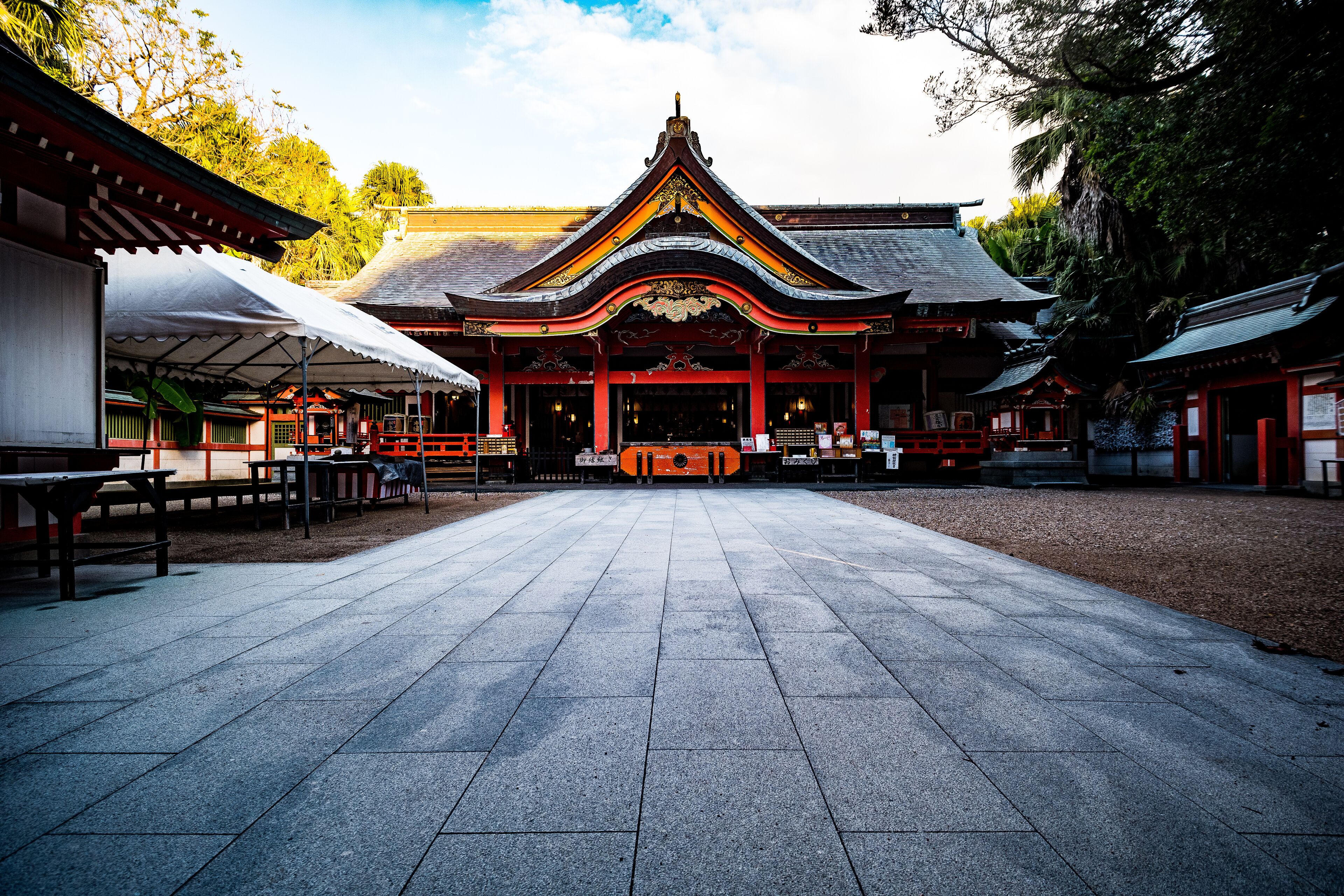 A traditional temple with a tiled courtyard, red and black architecture, and a central altar.