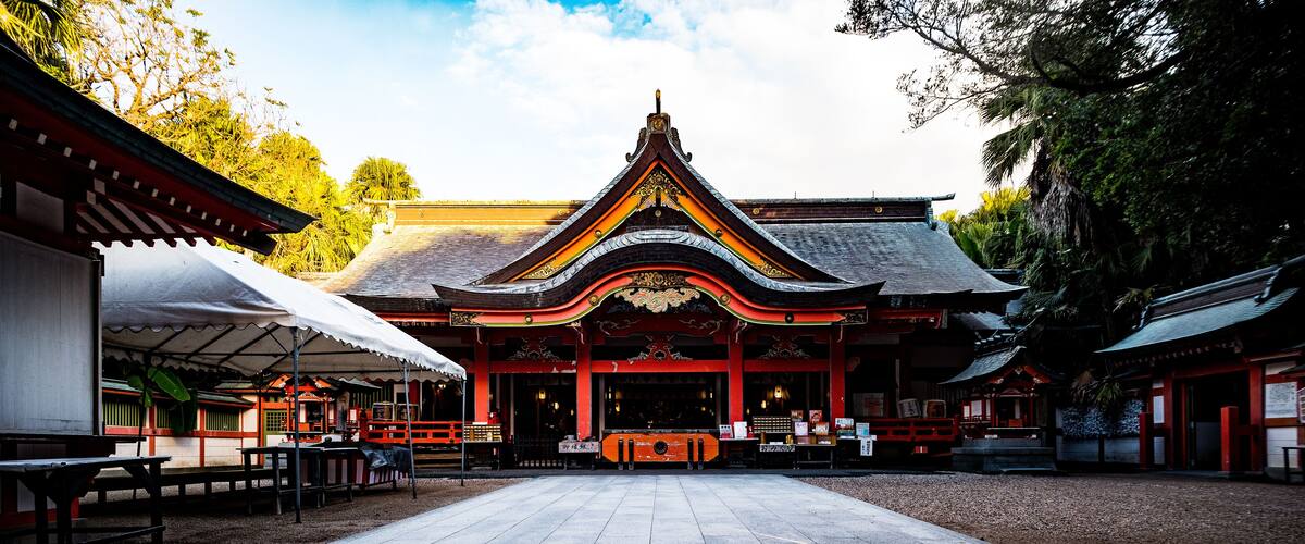 A traditional temple with a tiled courtyard, red and black architecture, and a central altar.