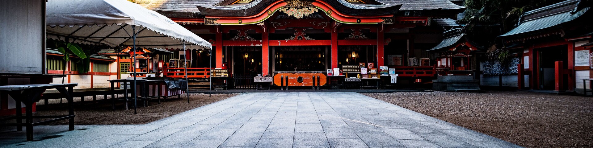 A traditional temple with a tiled courtyard, red and black architecture, and a central altar.