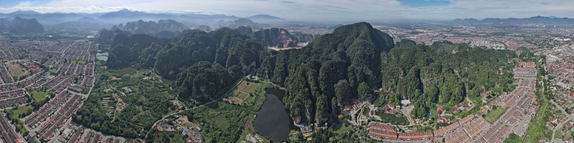 A panoramic view of a city surrounded by lush green mountains and a river.