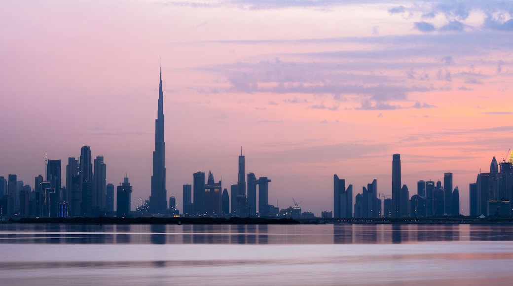 Stunning view of the Dubai skyline silhouette during sunset with the magnificent Burj Khalifa and many other buildings and skyscrapers. Silky smooth water flowing in the foreground.