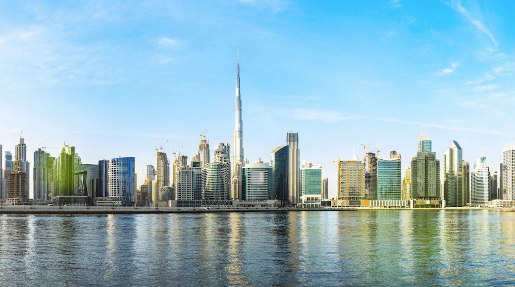 Stunning panoramic view of the Dubai skyline with the magnificent Burj Khalifa and many other buildings, skyscrapers and towers reflected on the Dubai water canal flowing in the foreground. Dubai