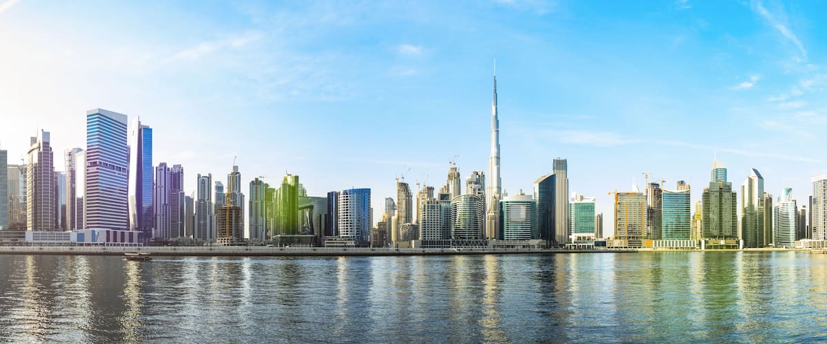 Stunning panoramic view of the Dubai skyline with the magnificent Burj Khalifa and many other buildings, skyscrapers and towers reflected on the Dubai water canal flowing in the foreground. Dubai