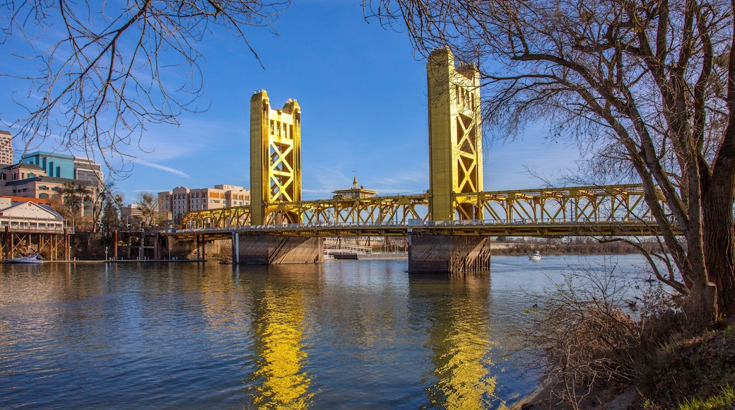 Un pont groc sobre un riu, amb edificis al fons.