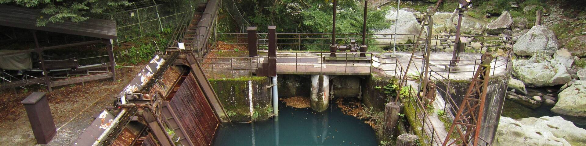 A lock system in a forested area with a bridge over a water channel.