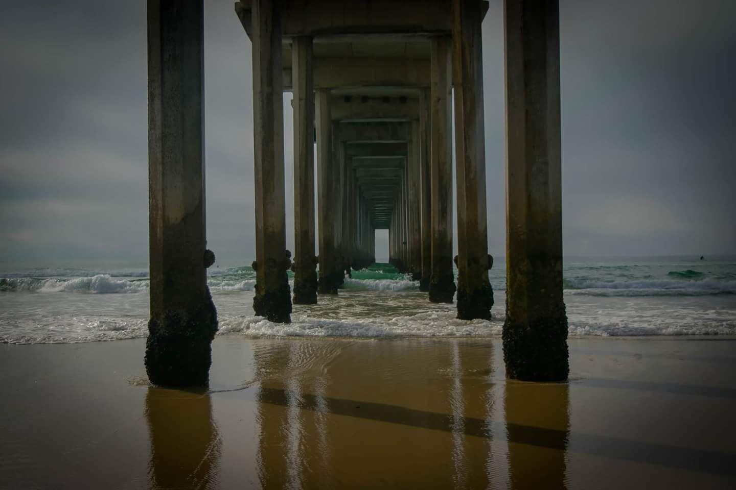 A pier extending into the ocean with waves crashing against it.