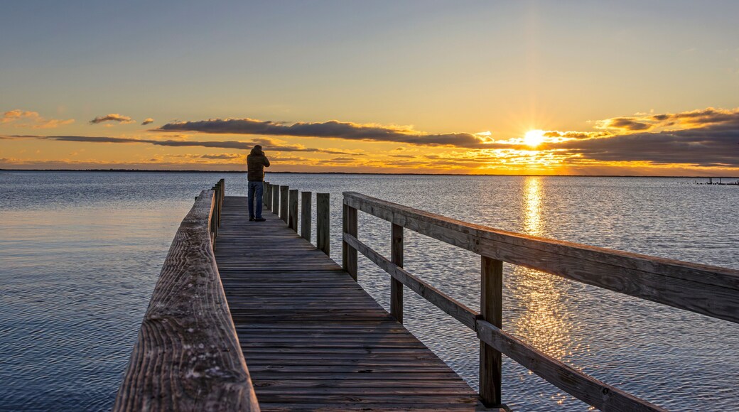 Man Standing At End Of Dock On A Bay At Sunrise Time