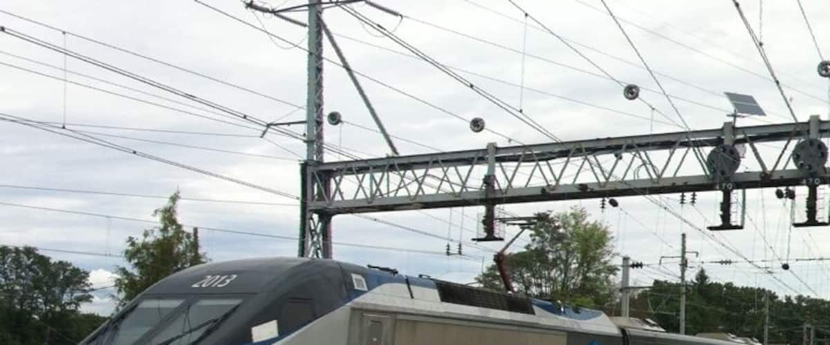 A silver and blue train with the number 2013 on the side, traveling on a railway track.