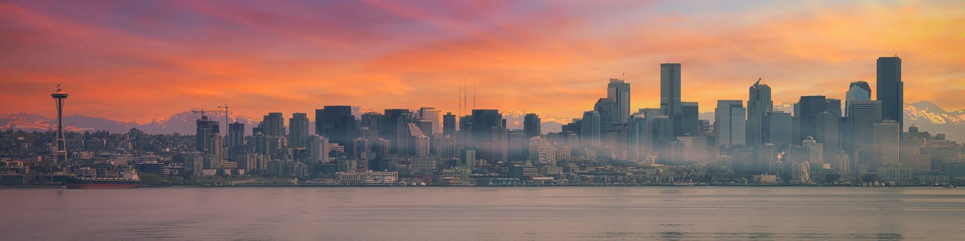 A city skyline at sunset with prominent skyscrapers and the Space Needle.
