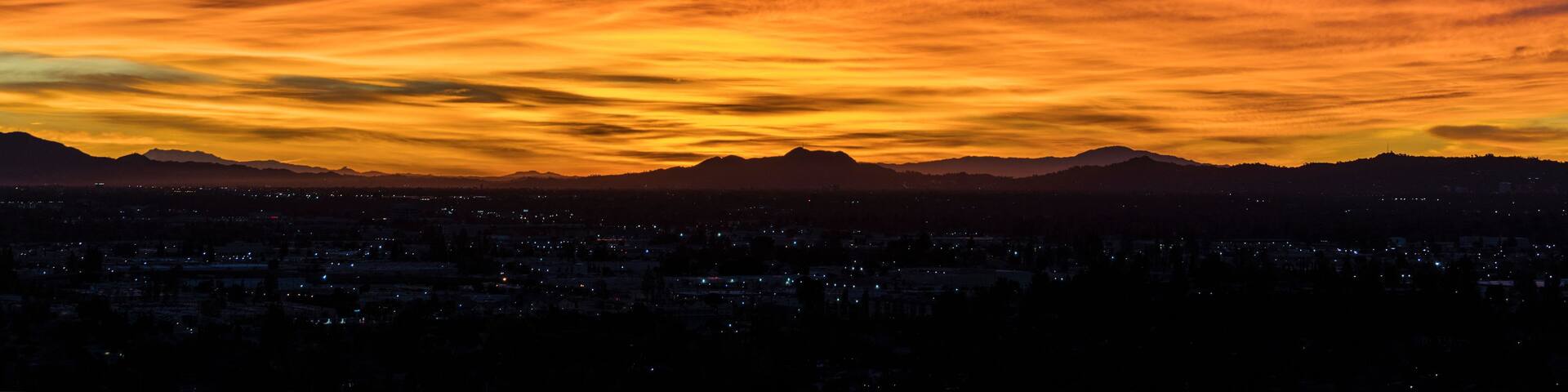 A sunset over a city with mountains in the background.