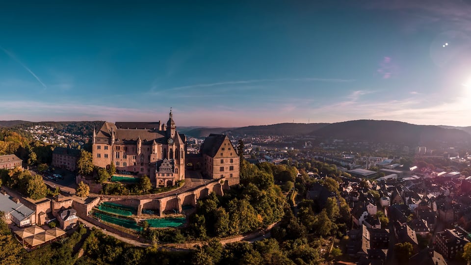 A historic castle surrounded by lush greenery and a river.