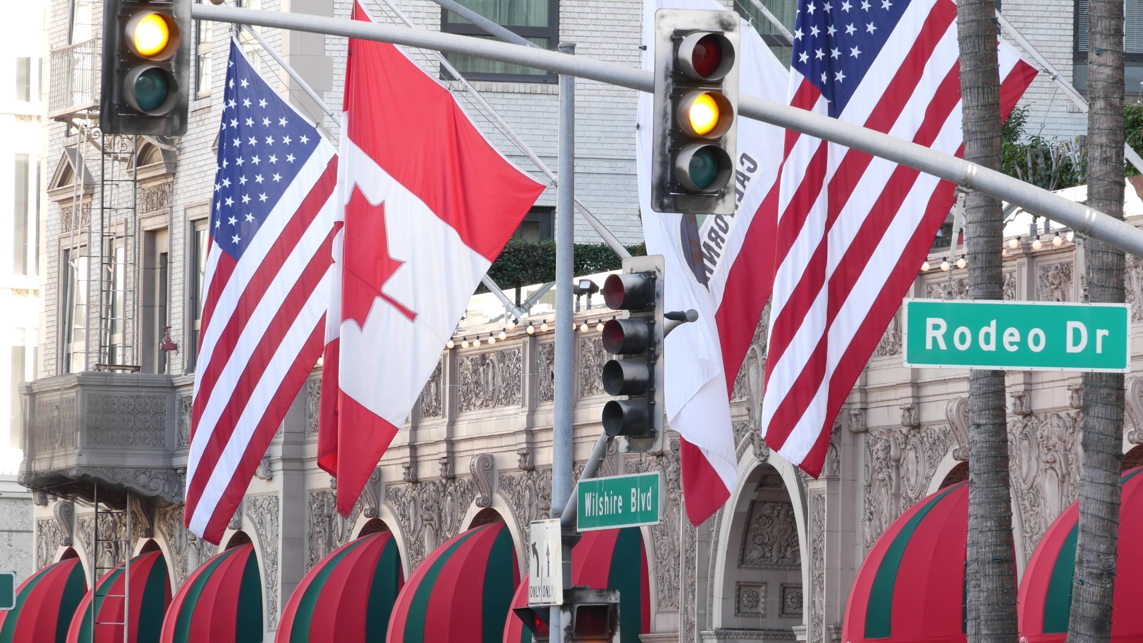 World famous Rodeo Drive Street Road Sign in Beverly Hills against American Unated States flag. Los Angeles, California, USA. Rich wealthy life consumerism, Luxury brands, high-class stores concept.