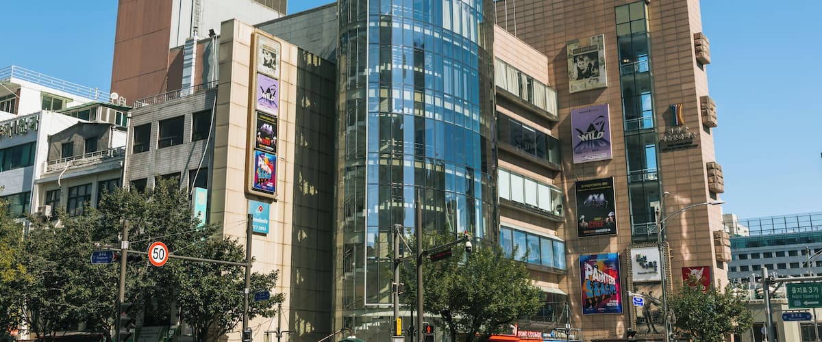 Horizonte urbano moderno com um edifício de vidro curvo imponente, diversos sinais comerciais e um céu azul límpido.