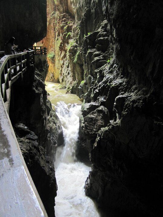 Um desfiladeiro estreito com uma cascata e uma ponte.