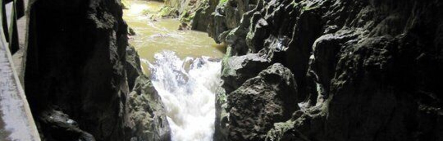 Um desfiladeiro estreito com uma cascata e uma ponte.