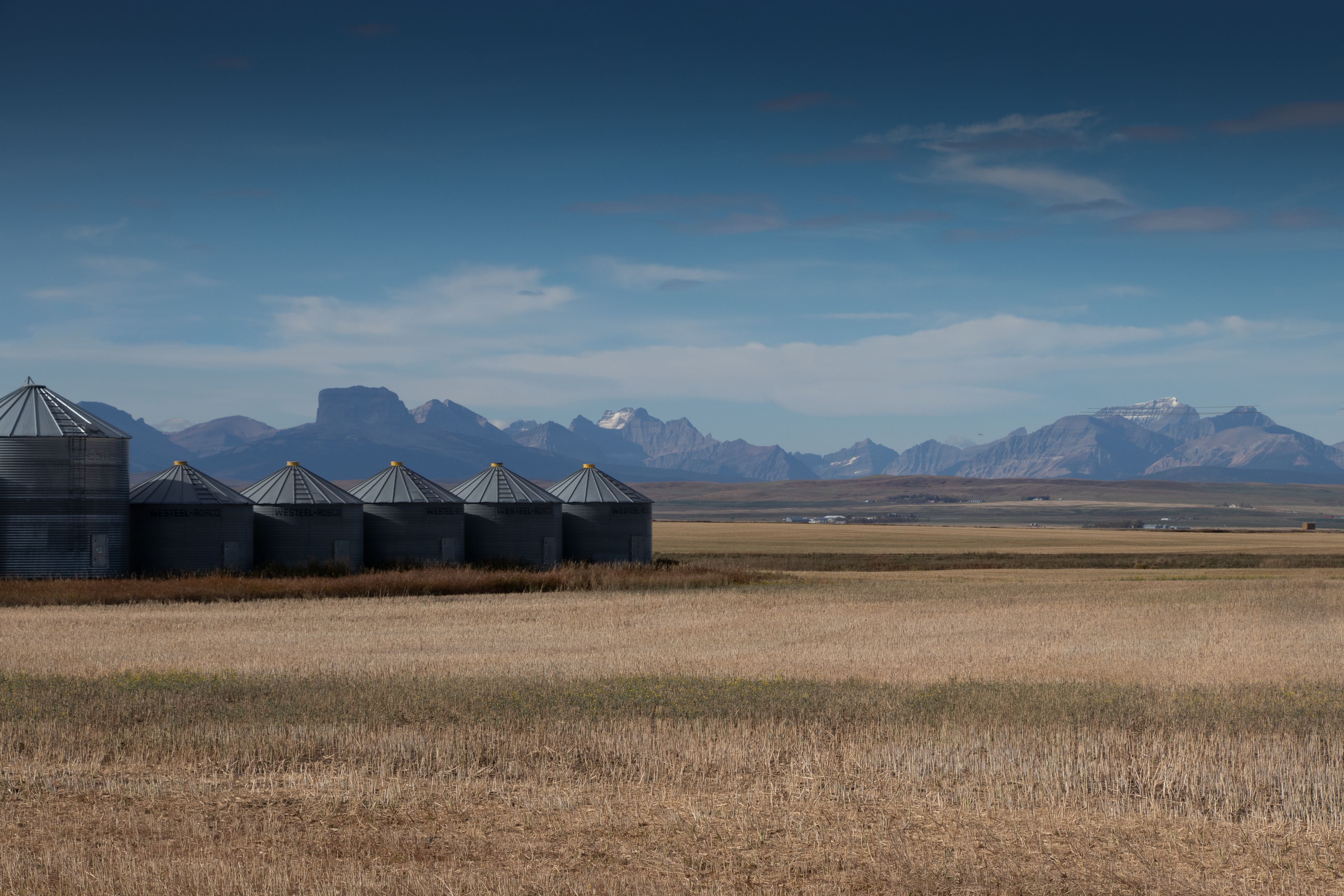 A grain silo field with mountains in the background.