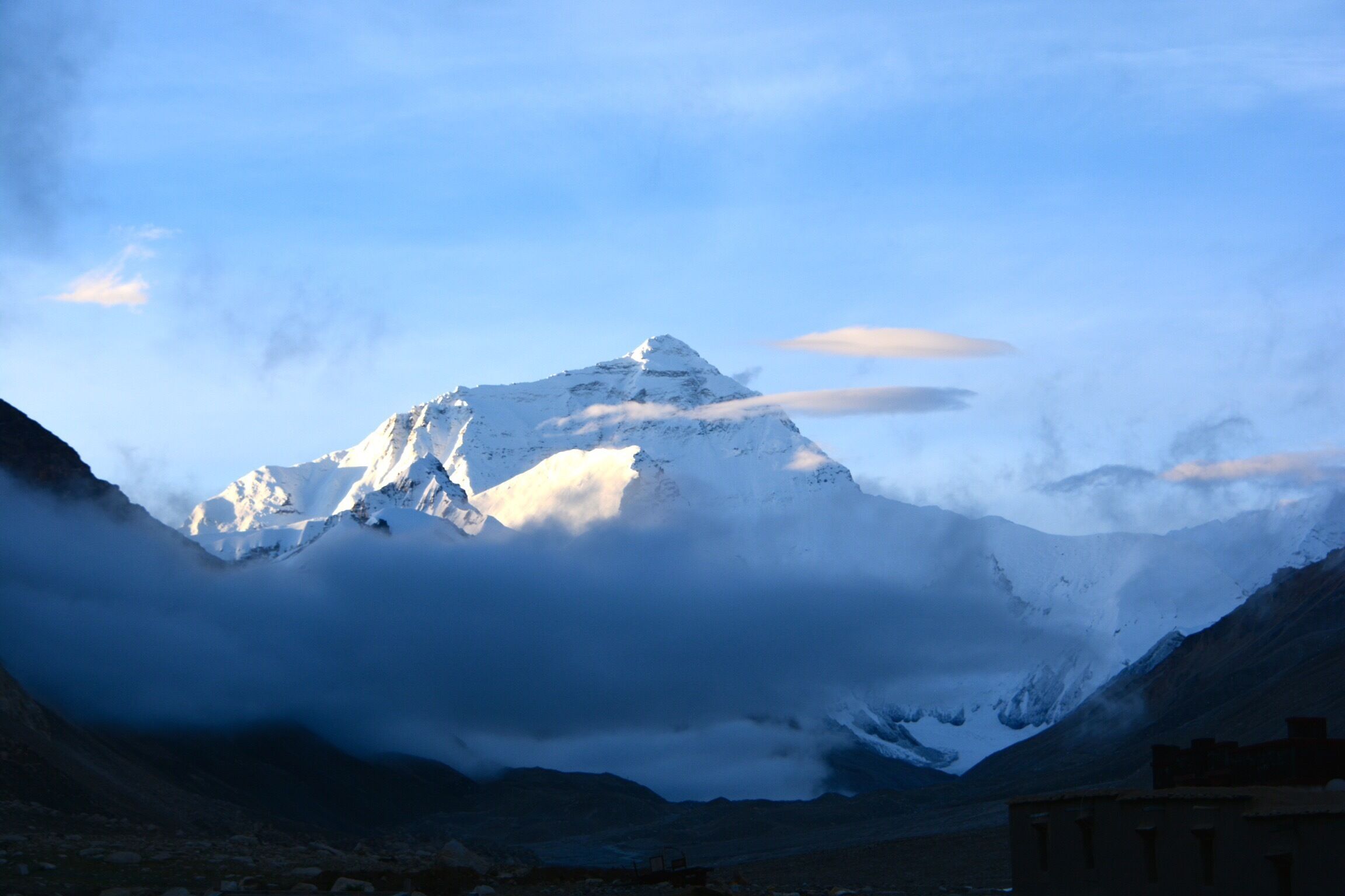 A snow-capped mountain peak with clouds at its base.