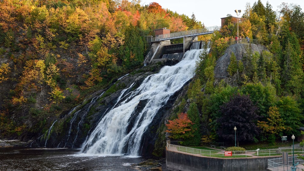 A waterfall cascading down a rocky cliff surrounded by autumn foliage.