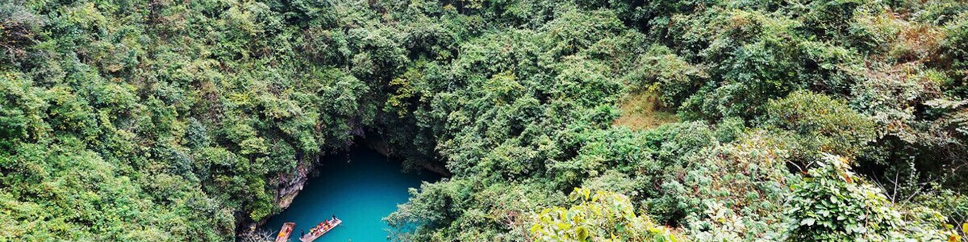 Um vale verdejante com um rio azul-turquesa e um barco.