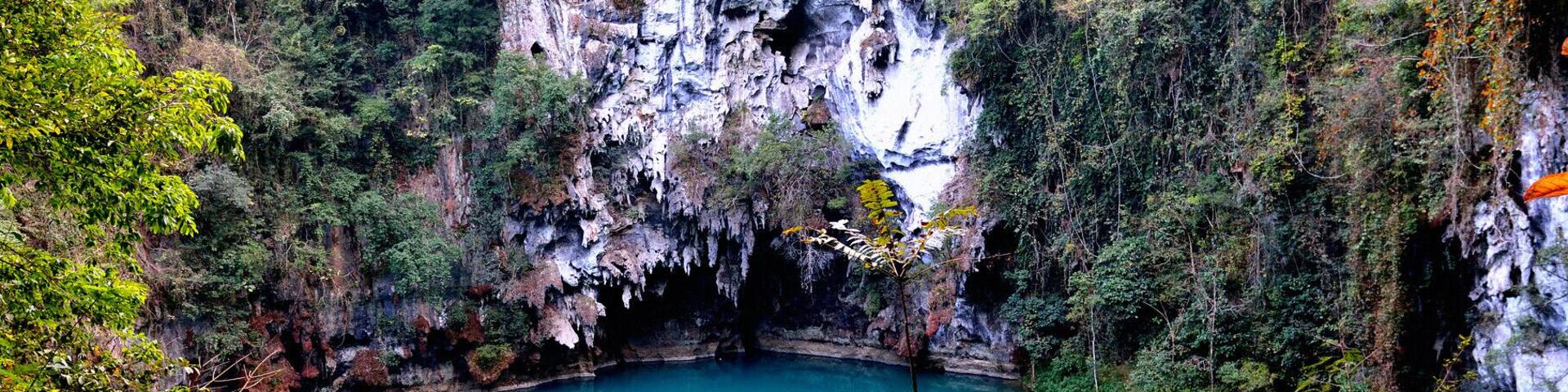 A turquoise lake surrounded by cliffs and dense foliage.