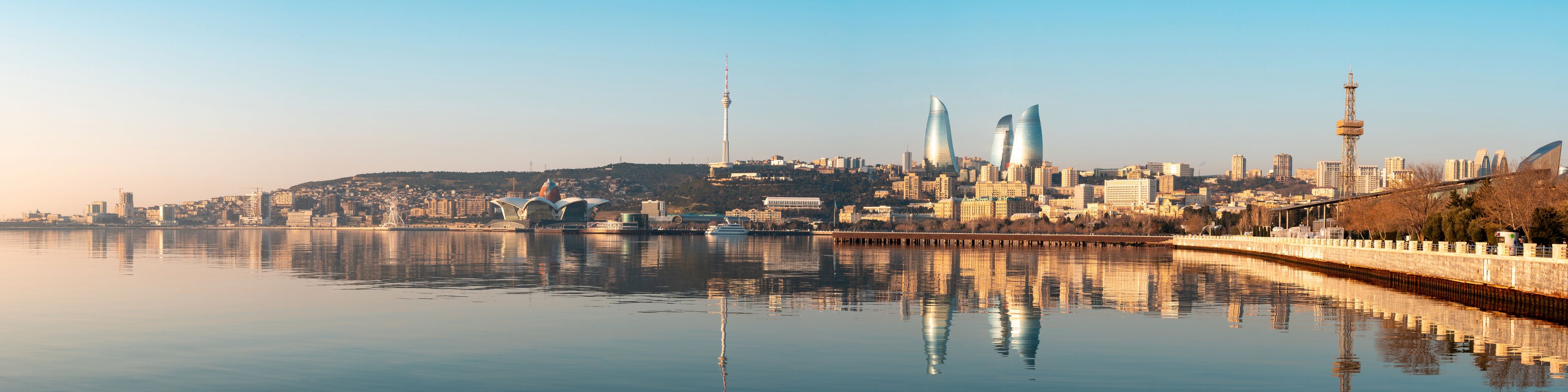 A cityscape with a river reflecting buildings, including a tower and modern architecture.