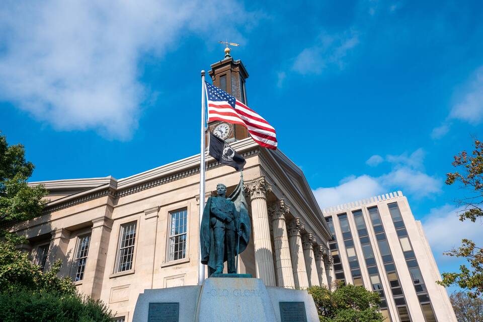 A building with a statue, an American flag, and a clock tower.