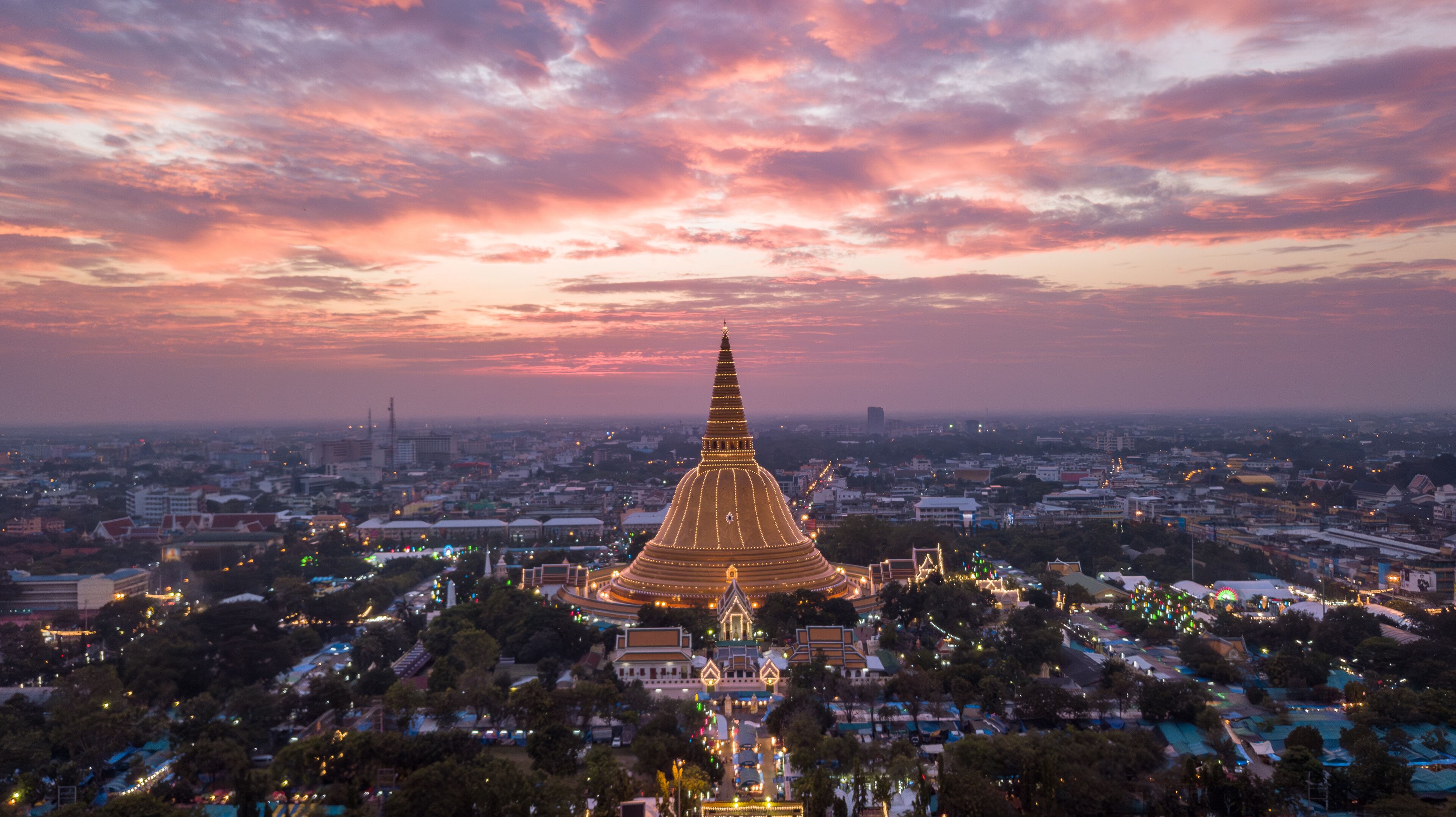 A cityscape with a prominent golden pagoda at sunset.