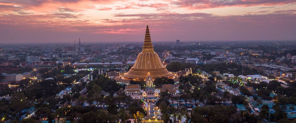 A cityscape with a prominent golden pagoda at sunset.