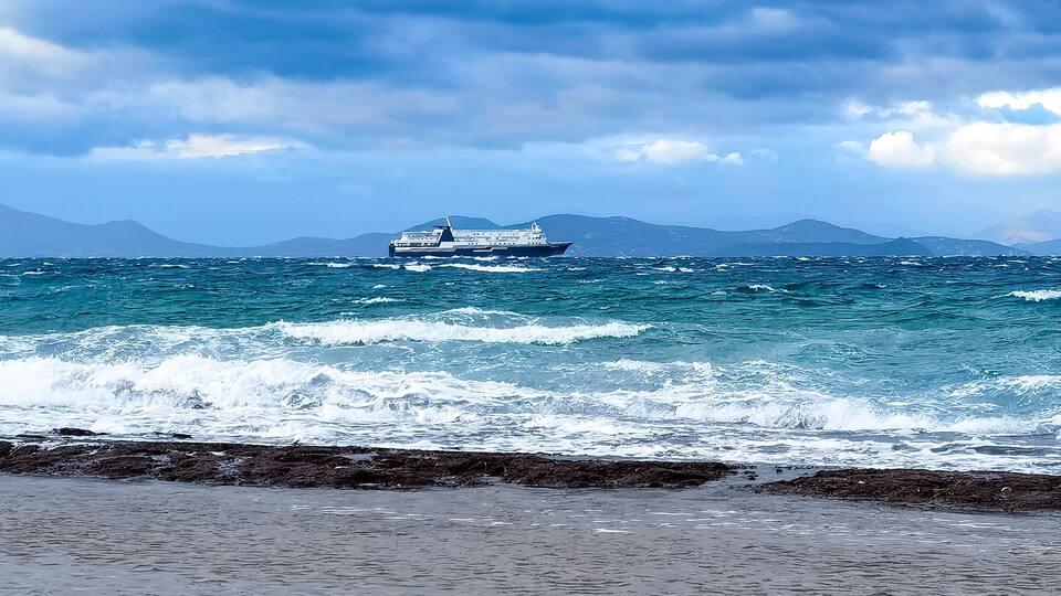 ferry boat floating on Aegean sea under a dramatic blue sky. Rafina city, Greece