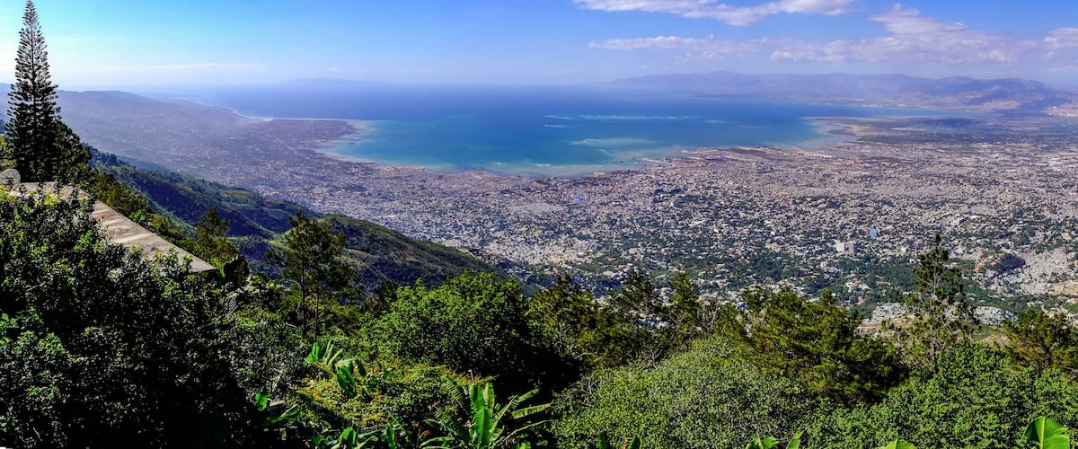 A coastal cityscape with a view of the sea and mountains.
