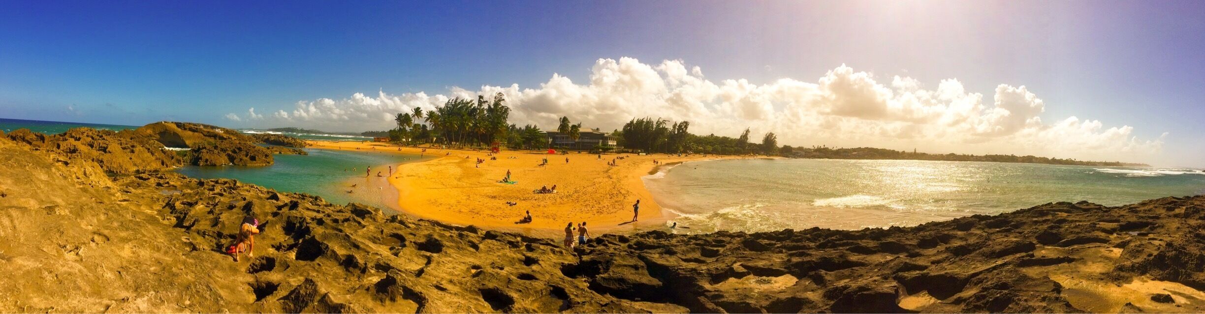 A beach with rocky terrain, a sandy area, and a clear blue sky.