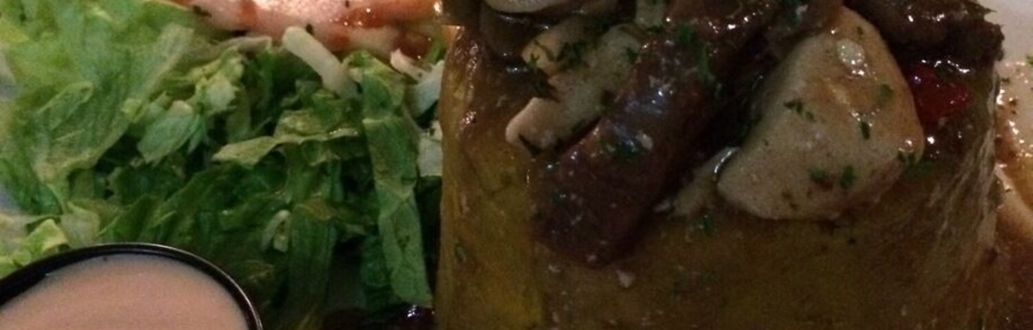 A plate with a meat dish, salad, and a small bowl of sauce.