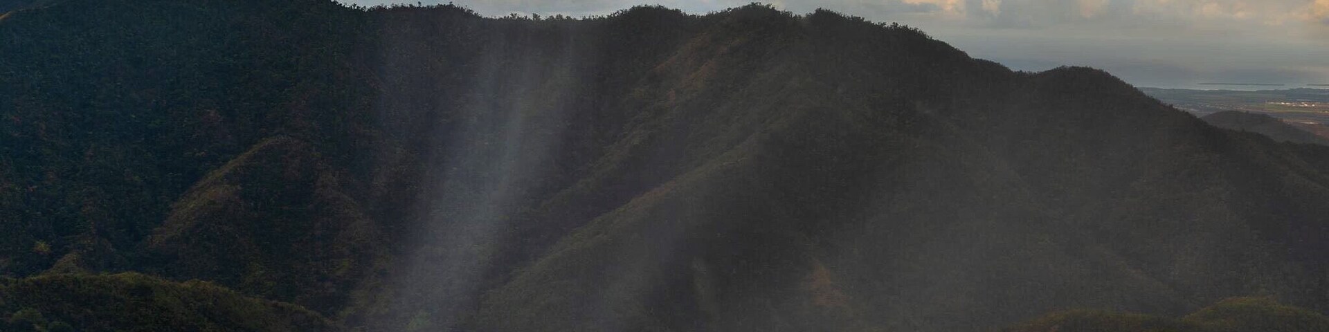 A valley with a small settlement surrounded by hills and a cloudy sky.