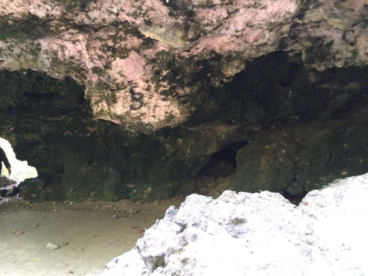 A cave entrance with rocky walls and a sandy floor.